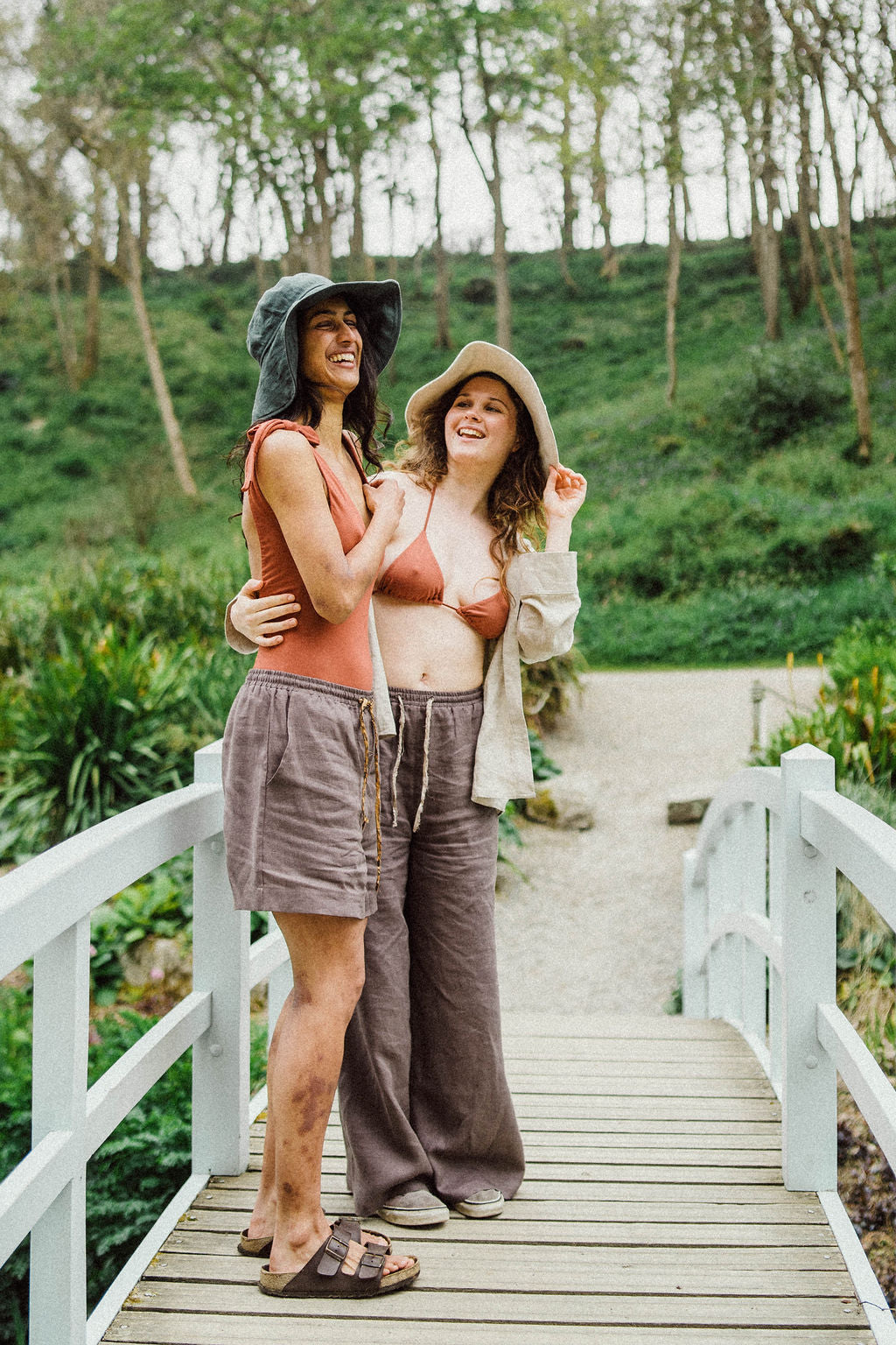 Solpardus laughter on Trebah gardens bridge in Cornwall. Nyx linen hat Thea bamboo onepiece Thea bamboo bikini top Atti linen shorts Atti linen trousers Saba linen shirt. All natural ethical sustainable sunwear swimwear linen clothing perfect for sensitive skin psoriasis and eczema