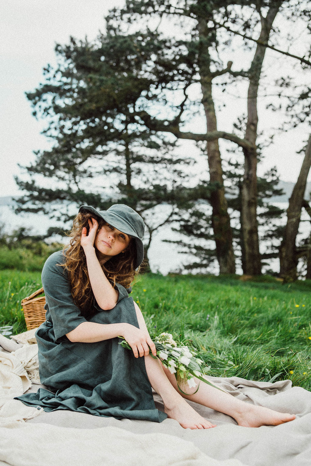 Solpardus Cornish coastal picnic in wild field with flowers. Nyx linen hat and Delphi linen dress. All natural ethical sustainable sunwear swimwear linen clothing perfect for sensitive skin psoriasis and eczema