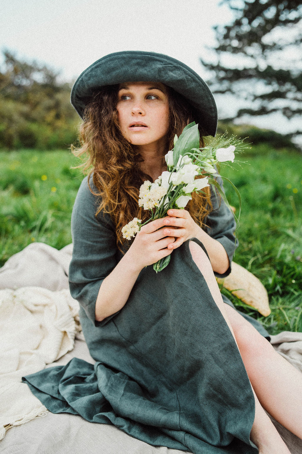 Solpardus picnic in Mawnan Smith Cornwall wearing Delphi linen dress and Nyx linen hat. Holding wild flowers. All natural ethical sustainable linen clothing perfect for sensitive skin psoriasis and eczema 