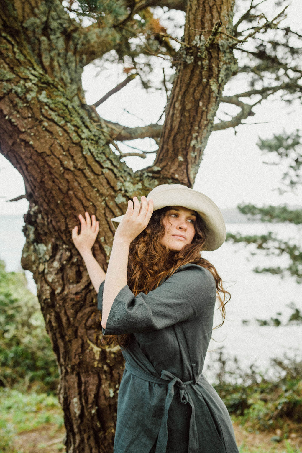 Solpardus in the trees by the shoreline at Mawnan Smith Cornwall. Nyx linen hat Delphi linen dress. All natural ethical sustainable sunwear swimwear linen clothing perfect for sensitive skin psoriasis and eczema